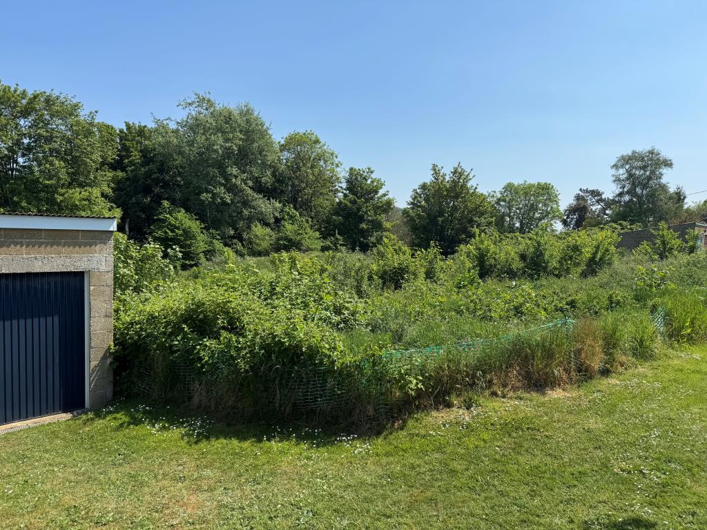 Lot: 28 - APPROXIMATELY THREE QUARTERS OF AN ACRE OF FREEHOLD LAND WITH POTENTIAL - Looking at the Site with the garages in View